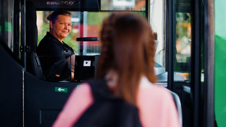 Jonge reiziger stapt in de bus bij vrouwelijke chauffeur