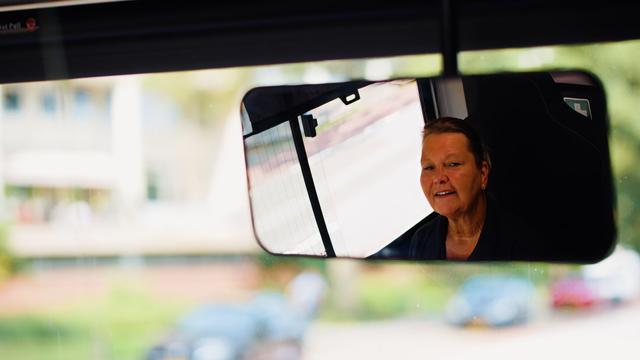 Chauffeuse kijkt in spiegel bus